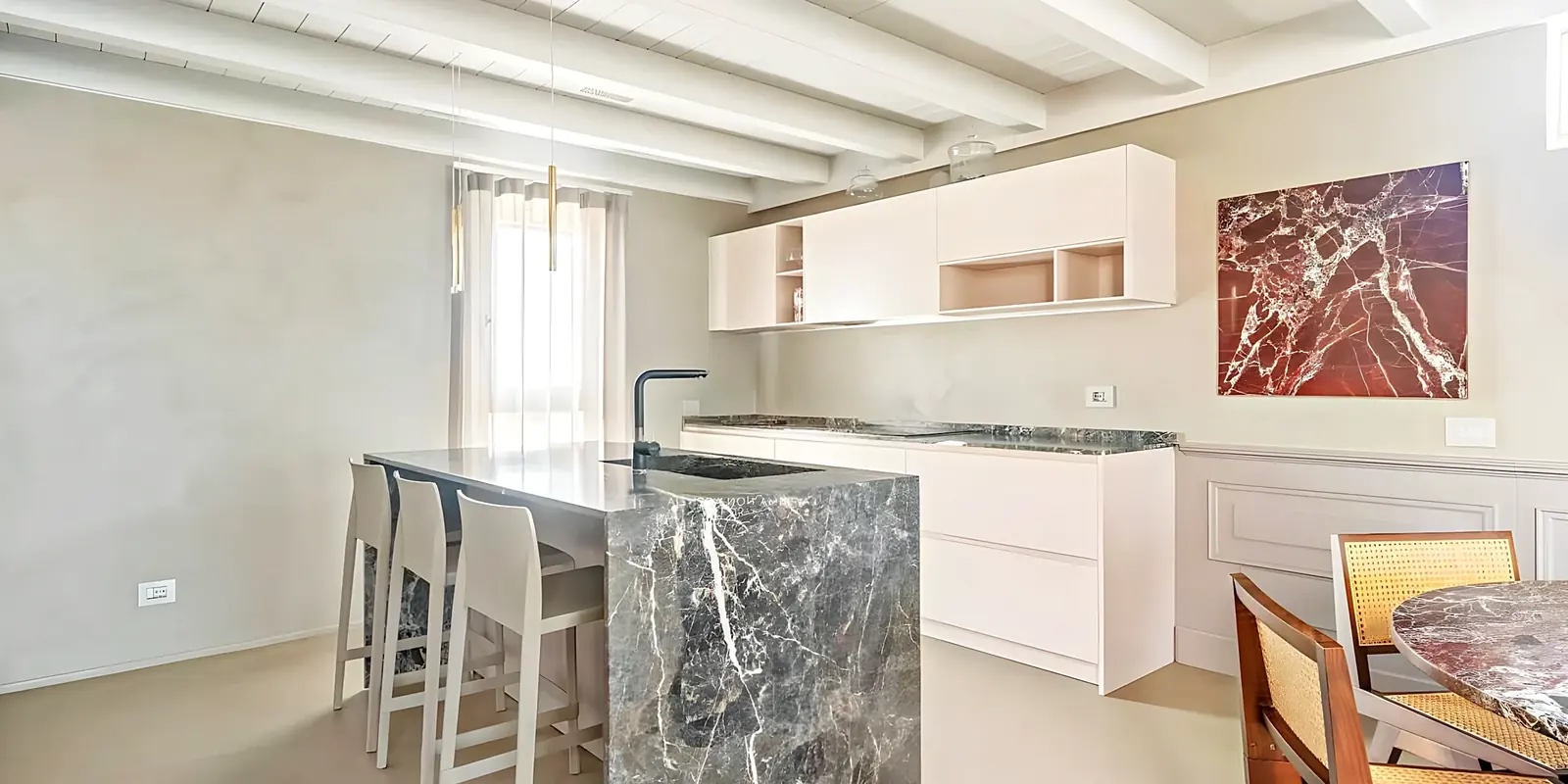Cocina abierta al comedor con isla de mármol gris y taburetes
