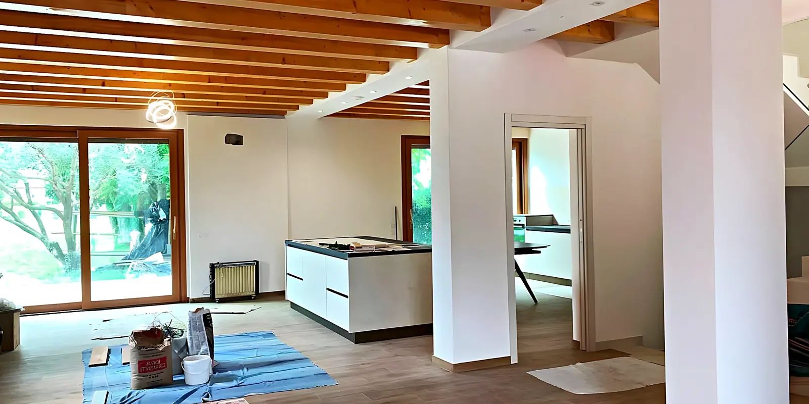 Salón y cocina en obra, con el pilar y la viga de acero ya montados bajo las vigas de madera