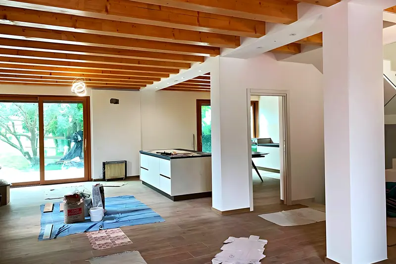 Salón y cocina en obra, con el pilar y la viga de acero ya montados bajo las vigas de madera