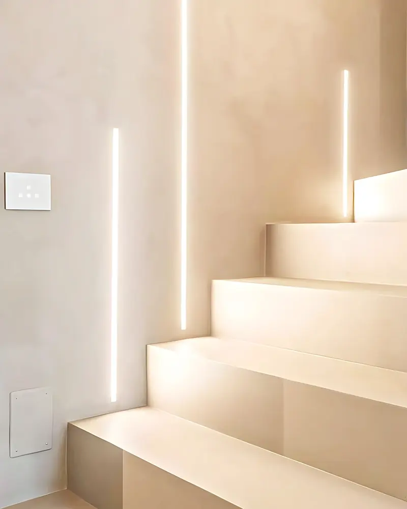 Arranque de la escalera revestido en microcemento con las tiras de luz empotradas