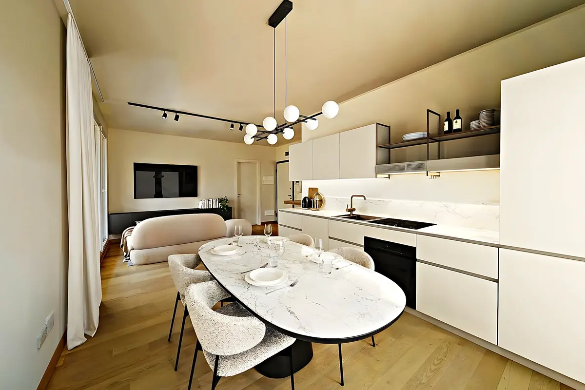 Cocina abierta al comedor con mesa ovalada de mármol y frentes blancos sin tirador
