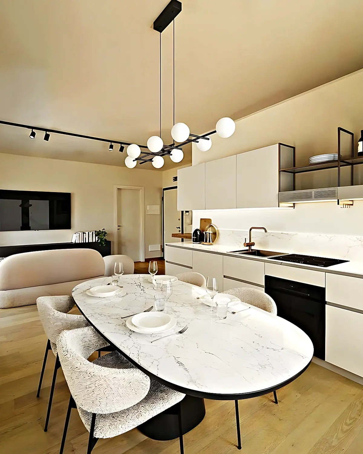 Cocina abierta al comedor con mesa ovalada de mármol y frentes blancos sin tirador