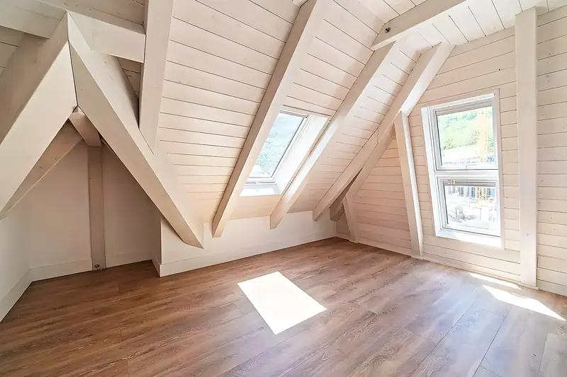 Buhardilla con la estructura terminada: cerchas y entablado de madera a la vista